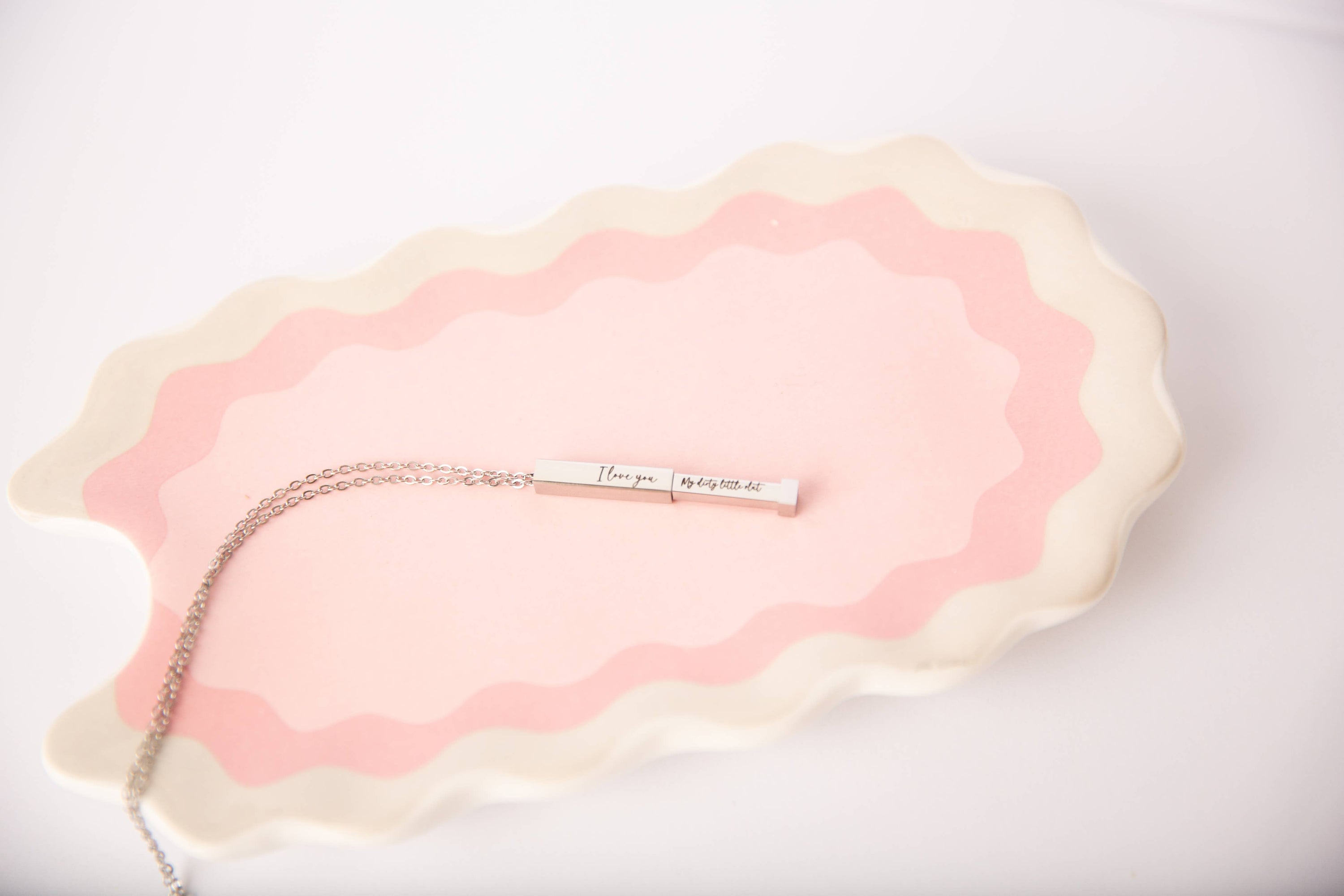 Necklace with a pendant on a pink and beige textured surface