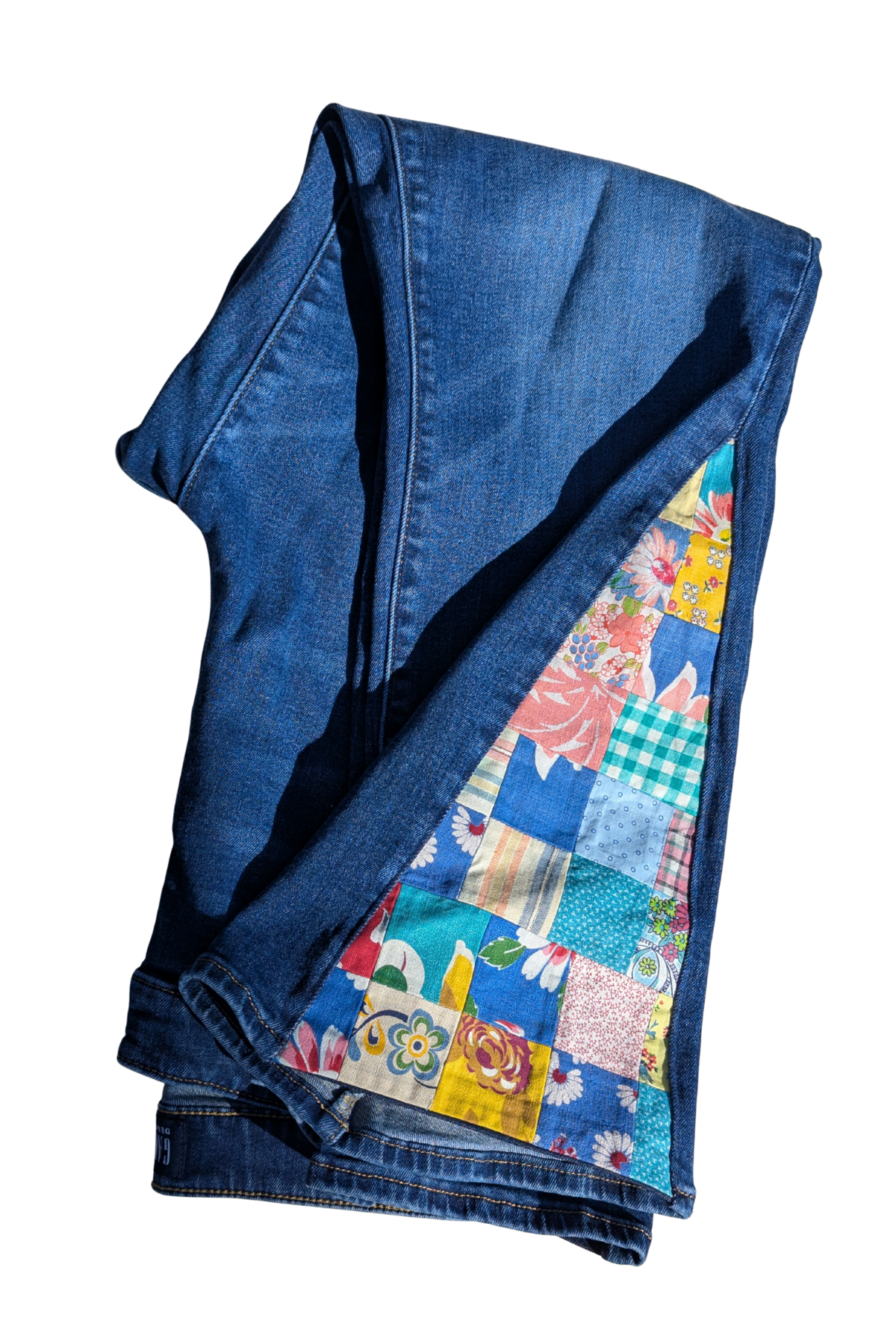 Folded blue denim fabric with a colorful patchwork lining on a white background