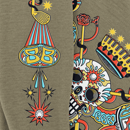 Close-up of a heather olive green fabric printed with a colorful graphic pattern featuring a stylized BB gun, stars, a snake, a crown, and a skull with floral details.