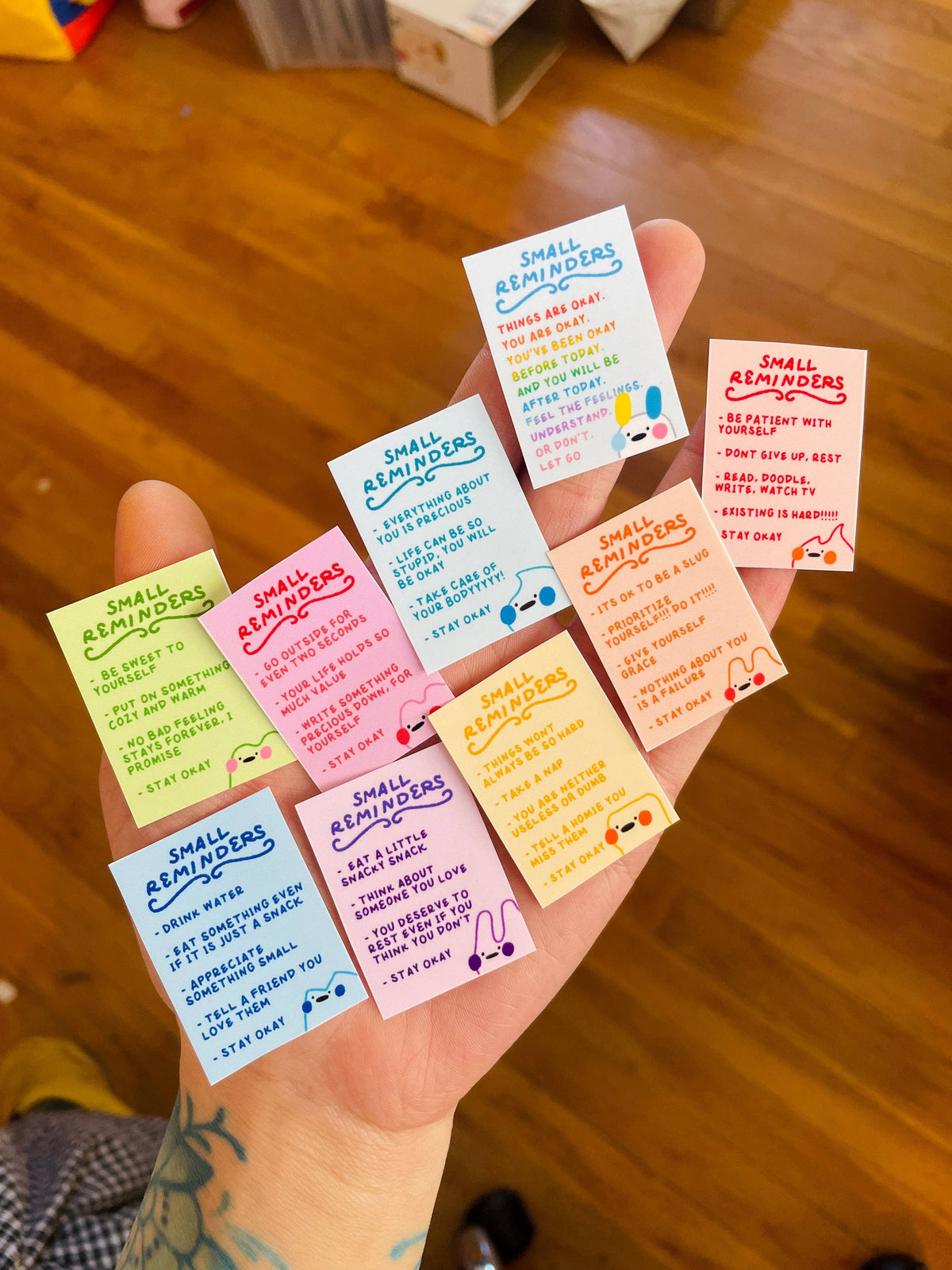 Hand holding colorful small reminders with text on a wooden floor background