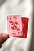 Queen of Books playing card held by a hand against a neutral background