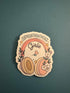 A die-cut sticker featuring a retro-style illustration with the words &