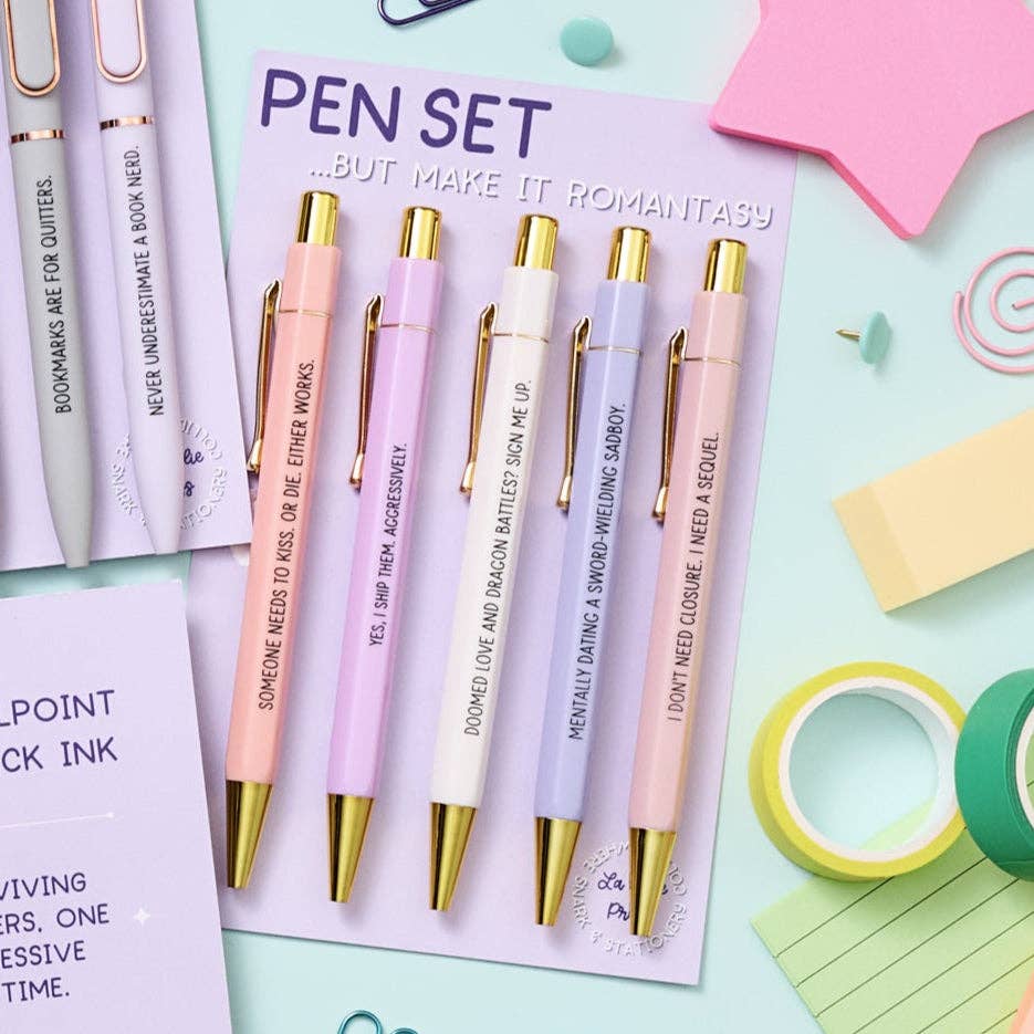 Set of pens with gold accents on a pink card with text, surrounded by stationery items.