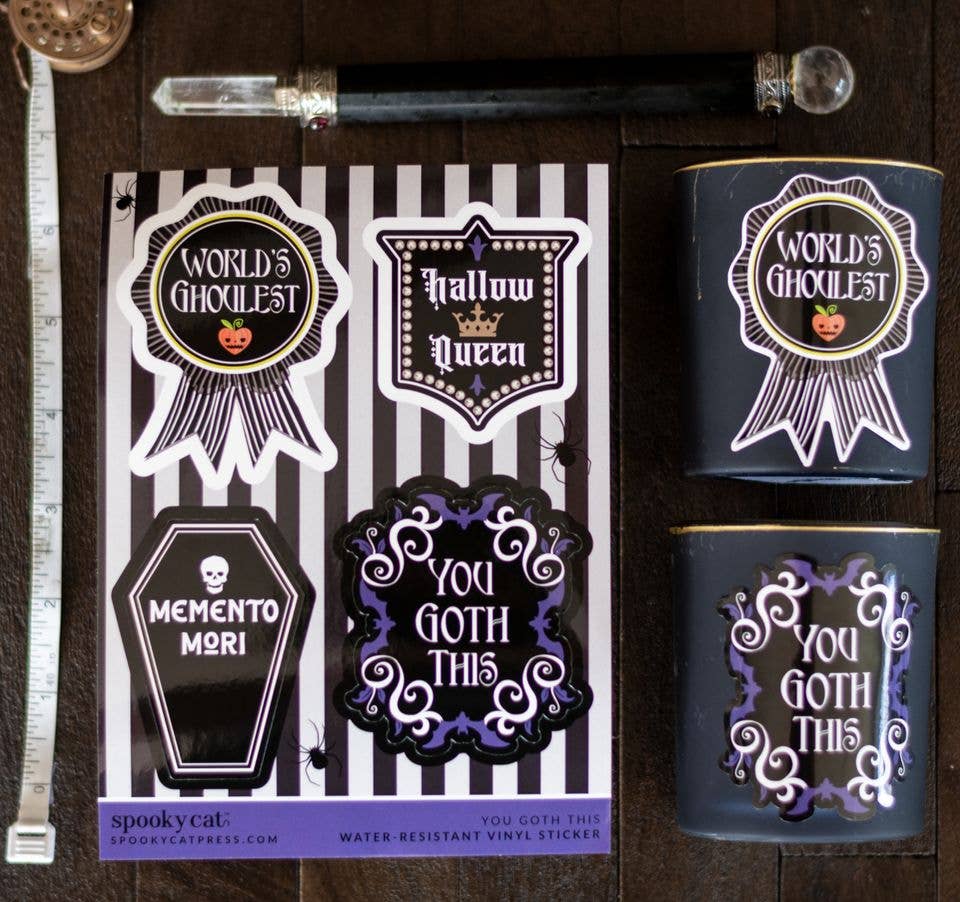 Halloween-themed vinyl stickers displayed on a dark wood background, including a sticker sheet with designs like &