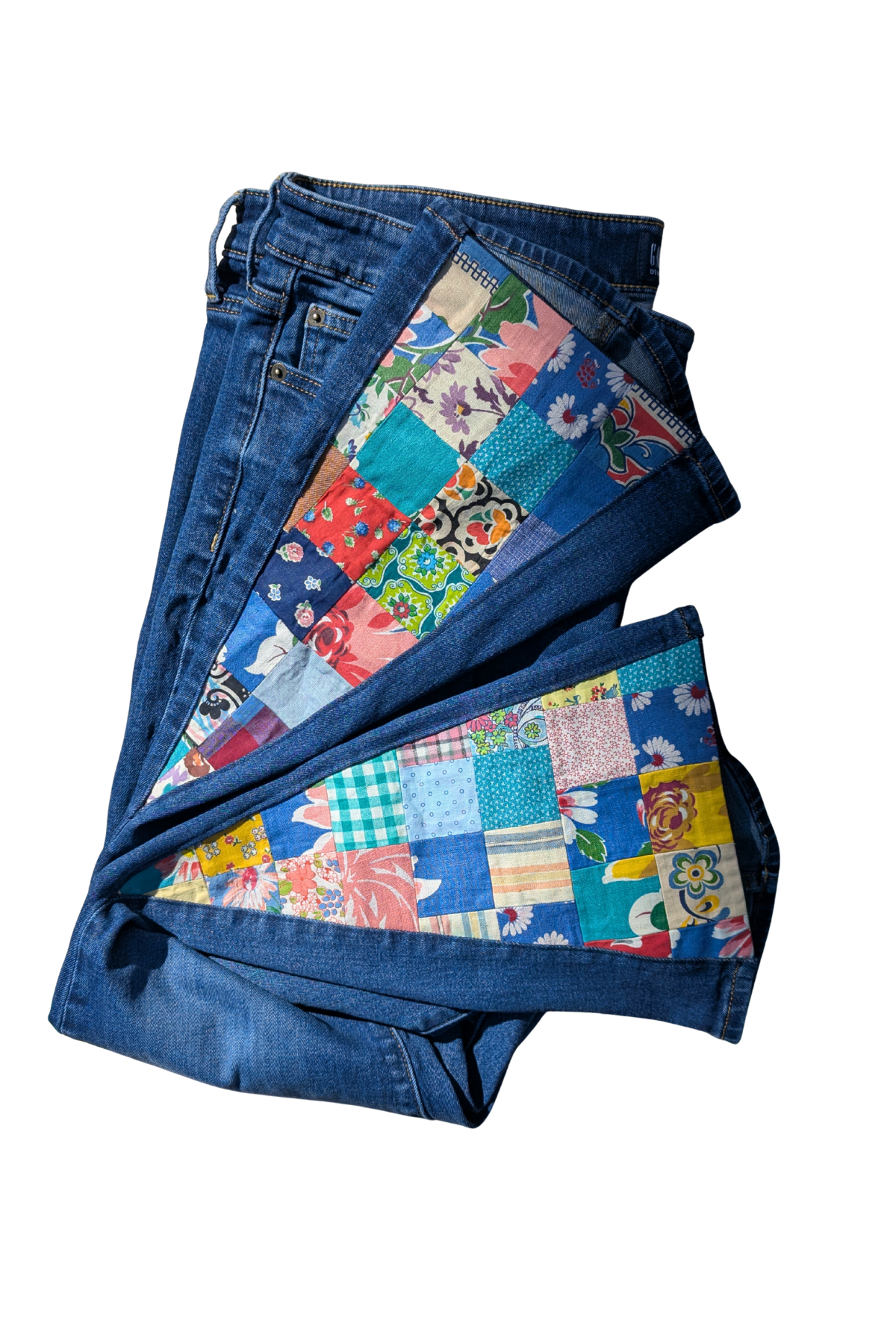 Pair of blue jeans with a colorful patchwork pattern on a white background