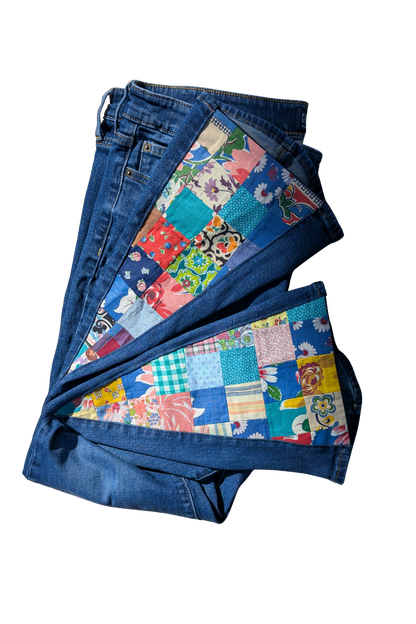 Pair of blue jeans with a colorful patchwork pattern on a white background