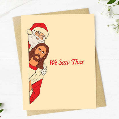 A cream-colored greeting card with a brown kraft envelope, featuring a cartoon illustration of Jesus Christ and Santa Claus peeking from behind a wall with the text &