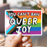 Hand holding a rainbow-colored sticker with text &