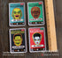 Four Halloween die-cut vinyl stickers featuring retro monster designs laid out on a dark wood surface next to a wooden ruler for scale. The stickers include Mr.