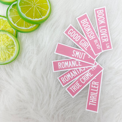 Pink book-themed stickers on a white surface with lime slices.
