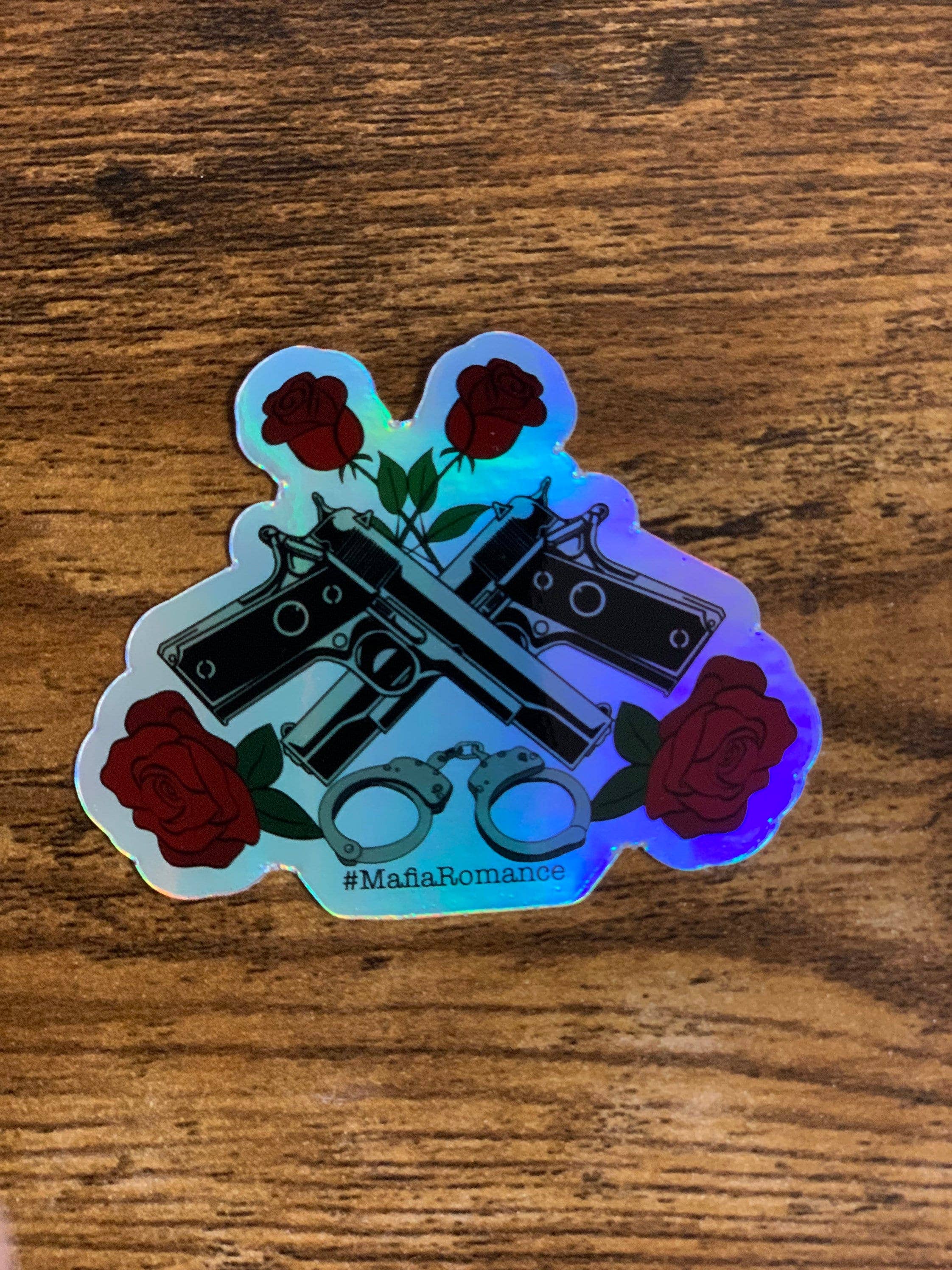 Holographic sticker with crossed revolvers and roses on a wooden surface