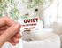 A hand holds a die-cut sticker shaped like a book page with the text &