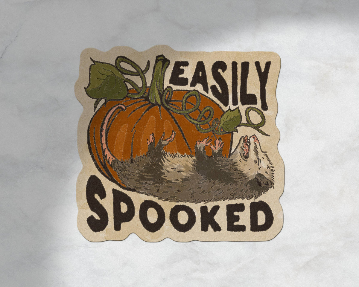 A die-cut sticker featuring a cartoon pumpkin and hedgehog with the text &