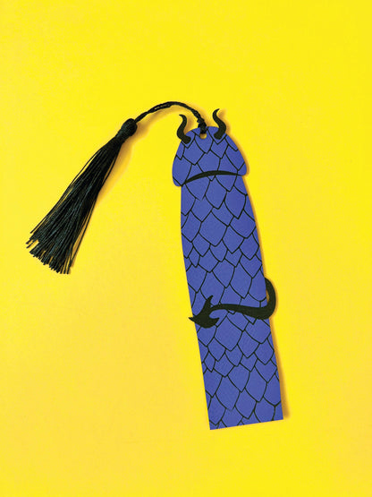 Blue dragon-shaped bookmark with a black tassel on a yellow background