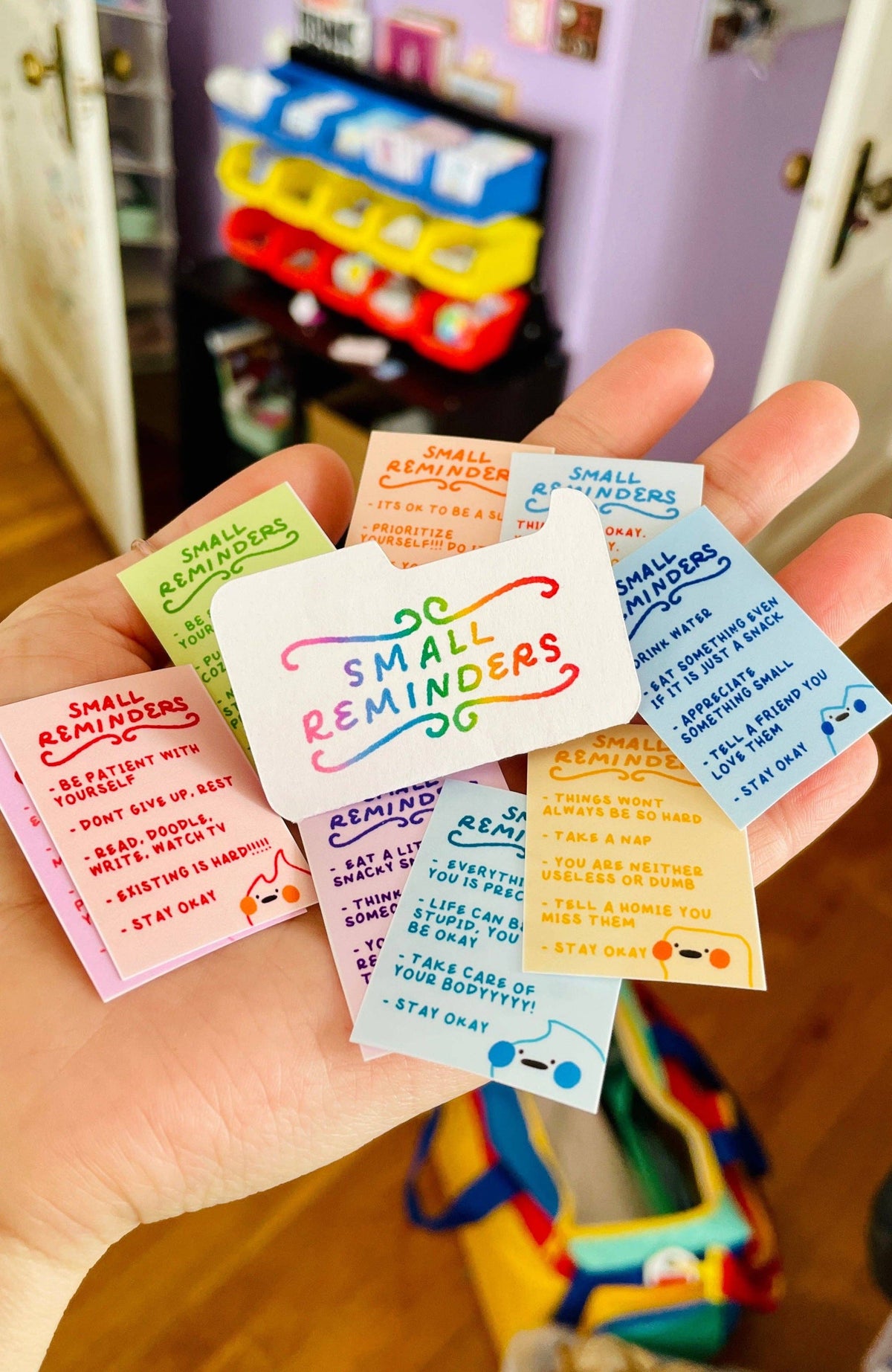 Hand holding small colorful reminder notes with text and graphics.