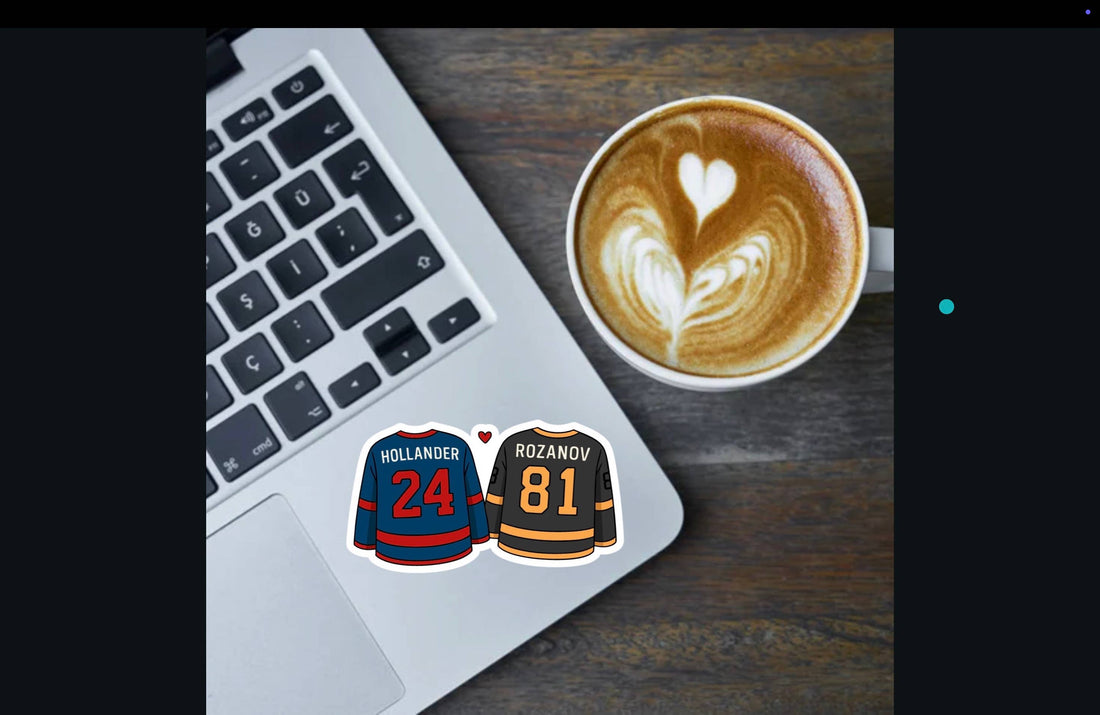 Laptop with hockey jerseys on stickers next to a cup of coffee with latte art.
