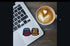 Laptop with hockey jerseys on stickers next to a cup of coffee with latte art.