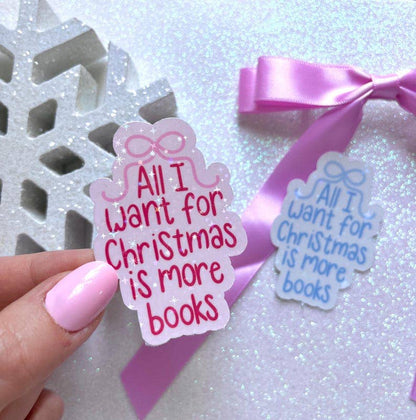 A hand with pink nail polish holds a scalloped gift box-shaped sticker that reads &