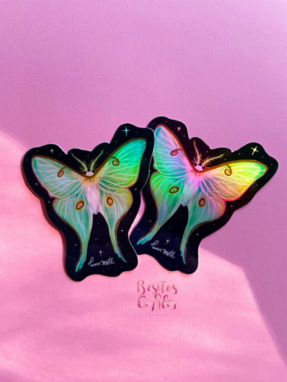 Two butterfly-shaped stickers with iridescent pastel wings on a black starry background, displayed on a pink surface with the text &