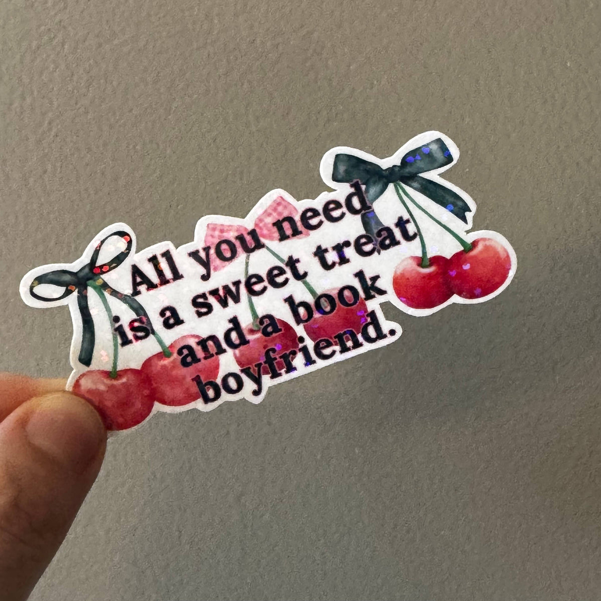 A hand holding a die-cut sticker with the quote &