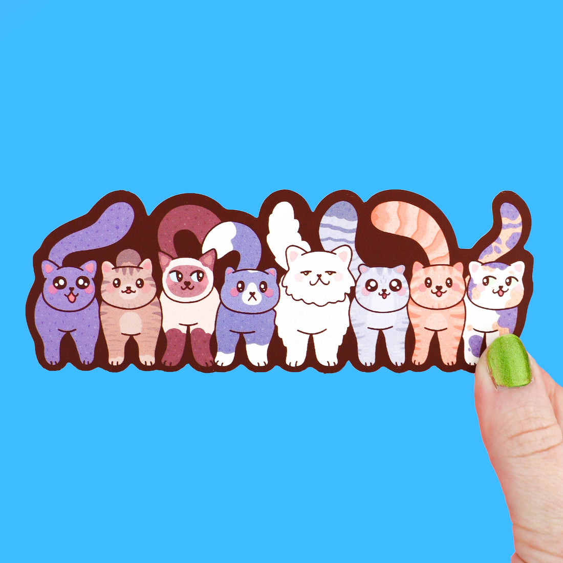 Cartoon cats bookmark held by a finger against a blue background