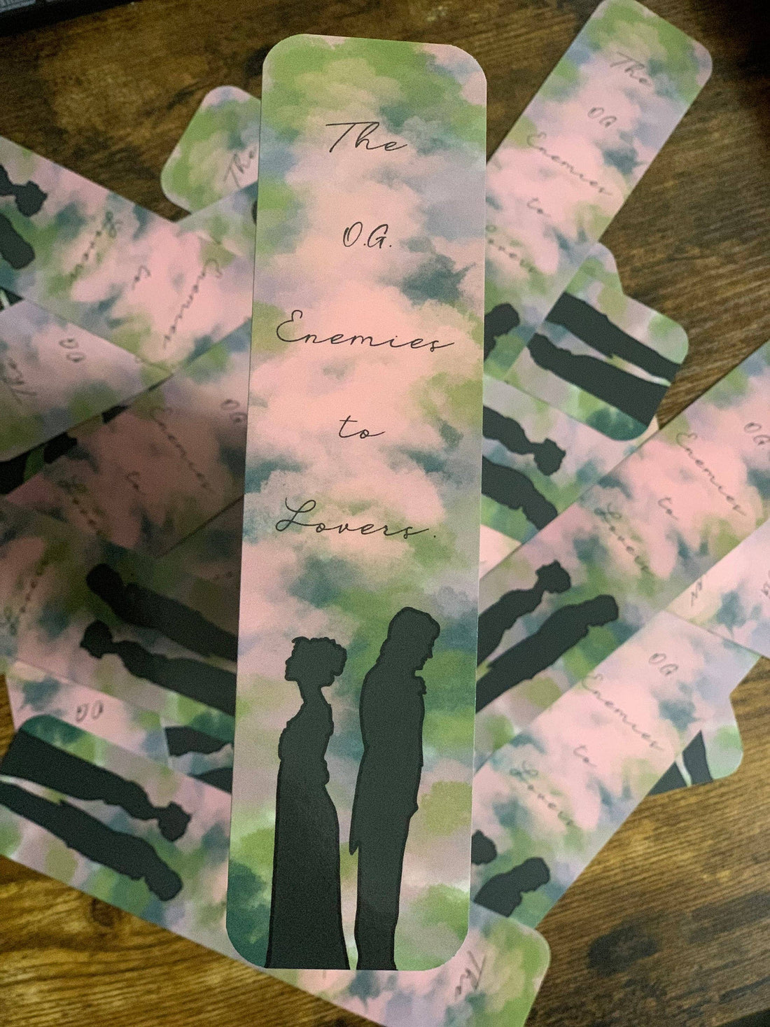 Bookmarks with watercolor designs and silhouette of a couple on a wooden surface