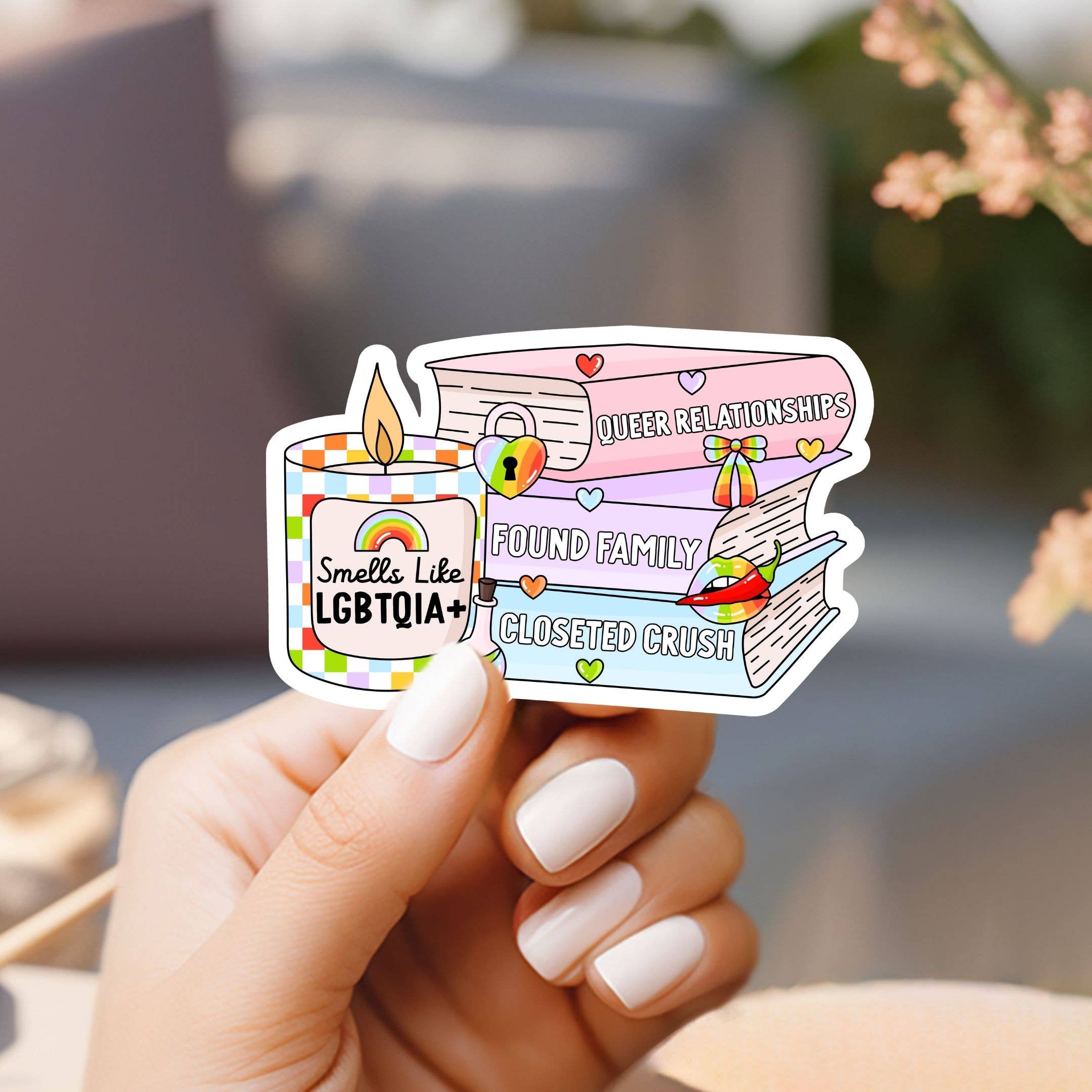 Hand holding a colorful sticker with LGBTQIA+ symbols and text.