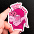 Sticker with a pink pumpkin character reading a book and &