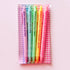 A set of five novelty highlighter pens in pink, teal, green, yellow, and orange, packaged in a clear plastic sleeve over a pink and white gingham patterned backing card. The pens feature bold, humorous feminist slogans printed vertically on their barrels.