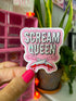 A hand with bright pink nail polish holds a die-cut sticker that reads &