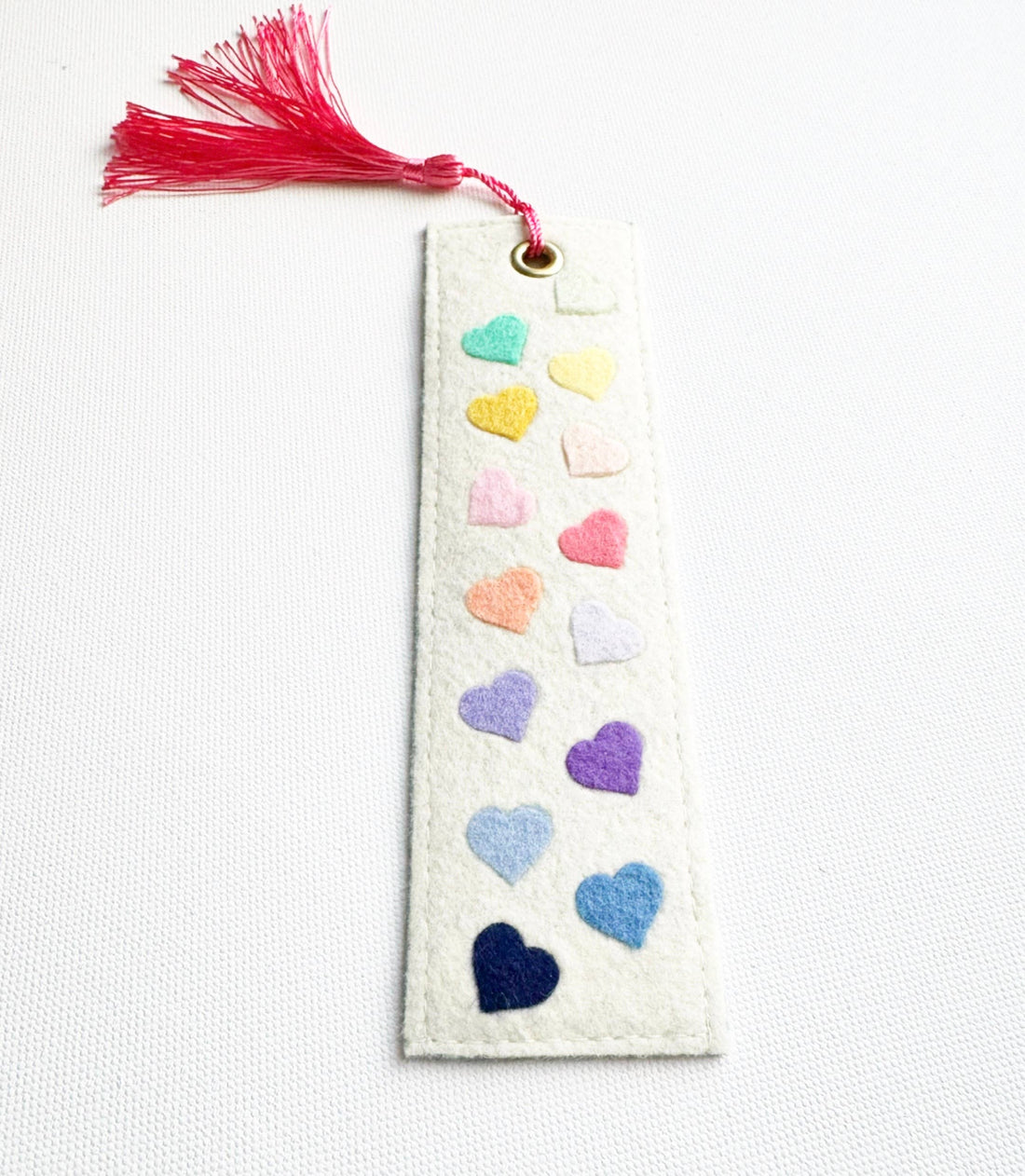 Bookmark with colorful heart patterns and a red tassel on a white background