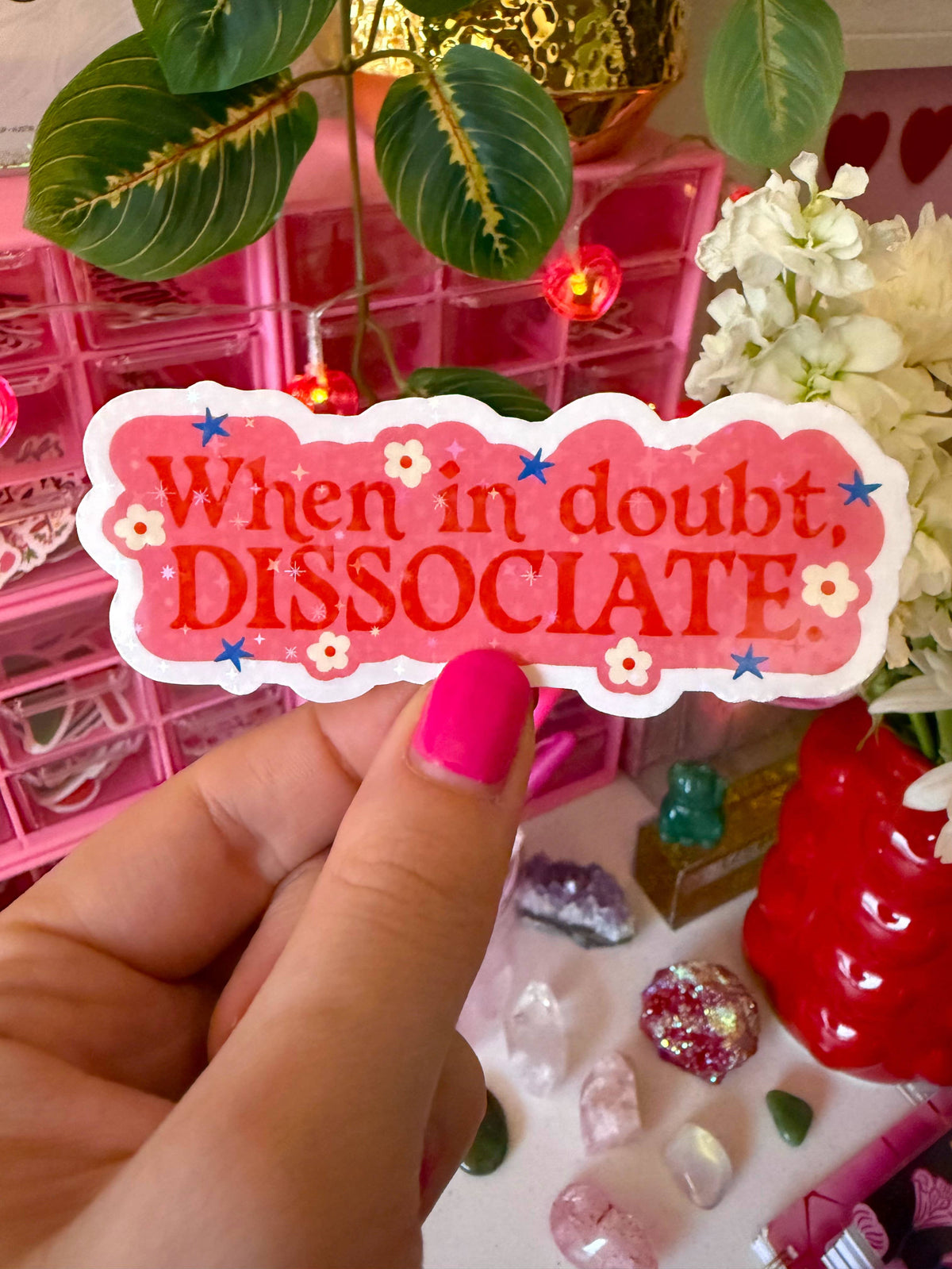 Hand holding a pink sticker with text &
