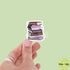 Hand holding a stack of books sticker with a green background