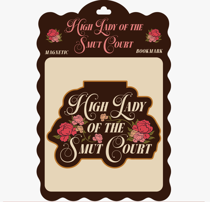 A decorative magnetic bookmark card with the phrase “High Lady of the Smut Court” in pink script and floral illustrations, shown on a plain light background.