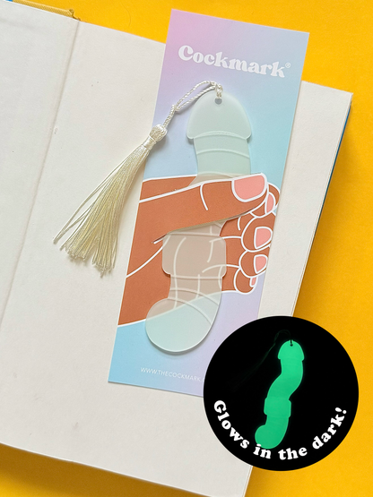 Glow-in-the-dark worm-shaped novelty bookmark with white tassel displayed in an open book.