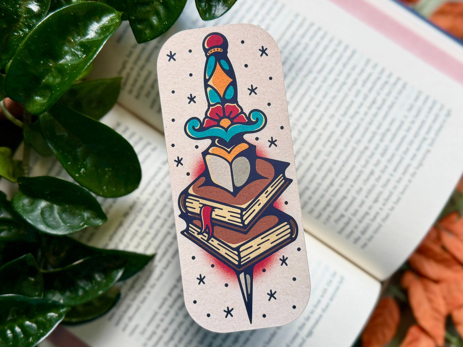 Colorful tattoo-style bookmark on an open book with a plant in the background