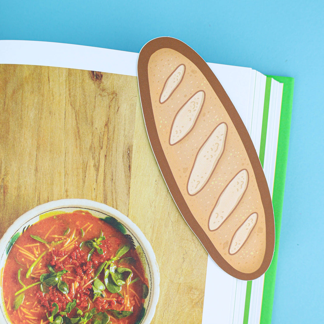 Illustration of a baguette and a bowl of soup on a wooden surface with a blue background