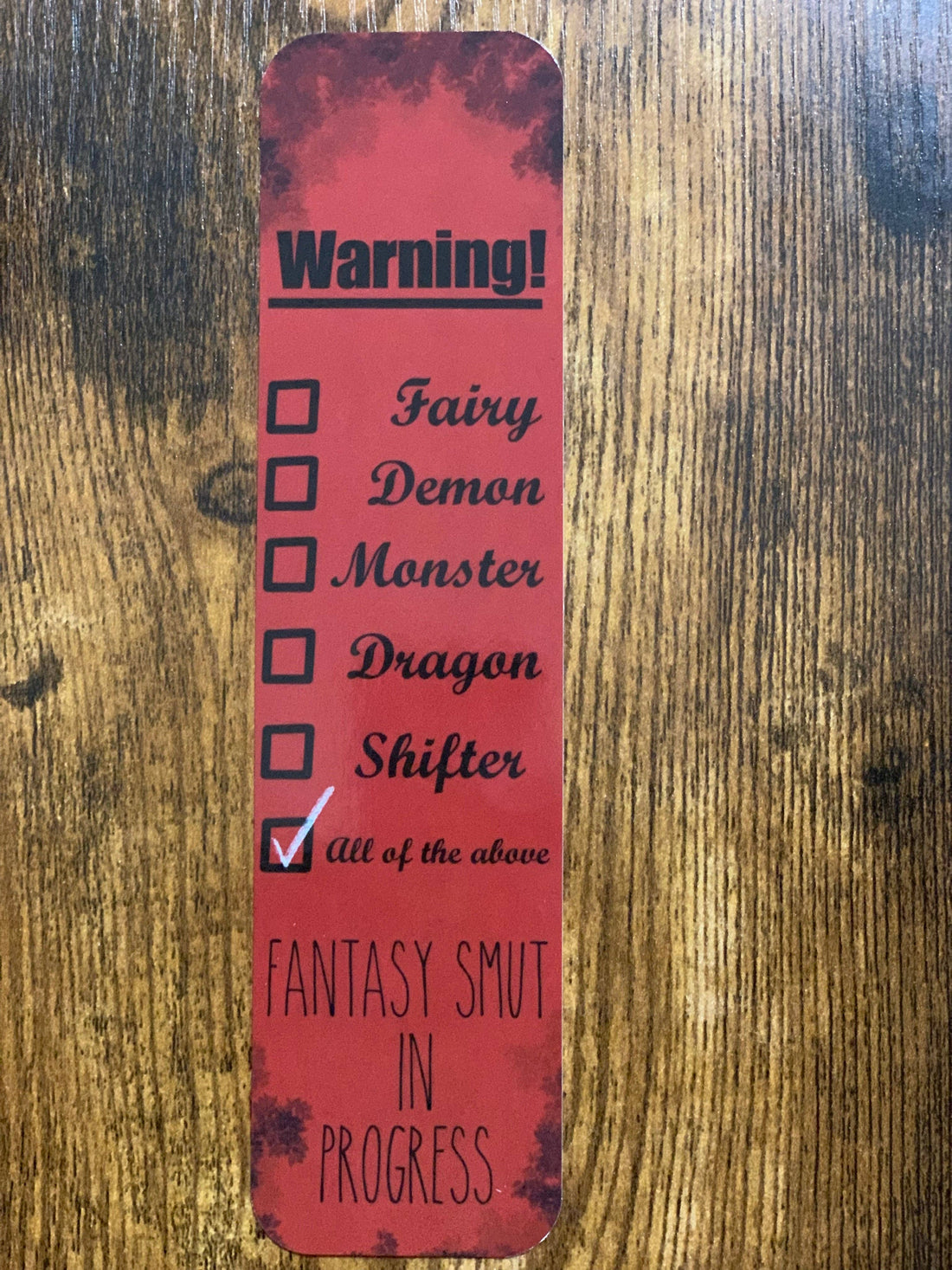 Red bookmark with text and checkboxes on a wooden surface