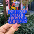 Blue sticker with text held by a hand in front of a colorful mural.