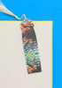 Colorful fish-shaped bookmark with a tassel on a blue and beige background