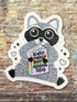Sticker of a raccoon holding a book with text on a brick wall background