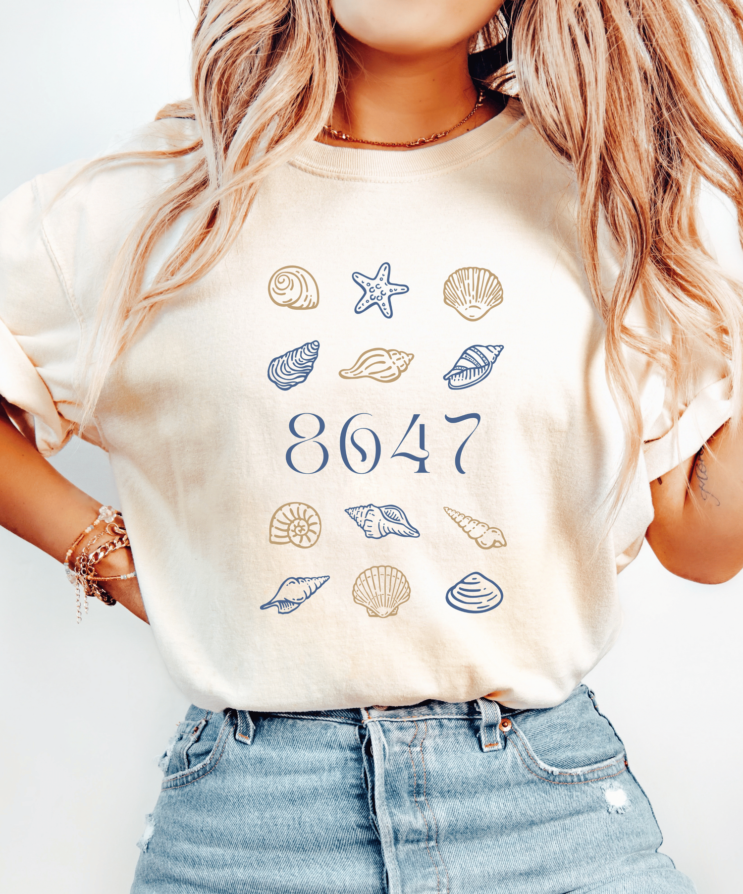 Person wearing a t-shirt with 8647 surrounded by seashell graphics