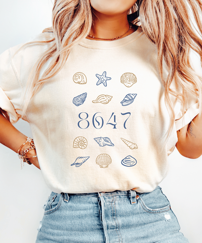 Person wearing a t-shirt with 8647 surrounded by seashell graphics