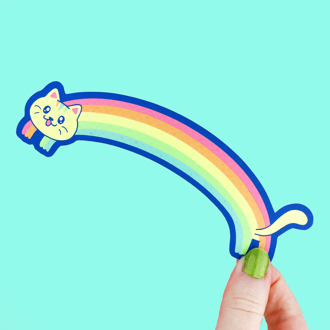 Colorful rainbow-shaped cat bookmark held by a hand against a teal background