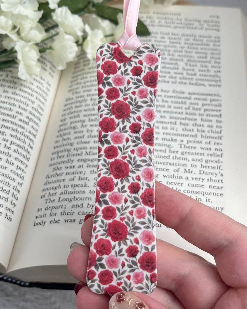 Floral bookmark held over an open book with white flowers in the background