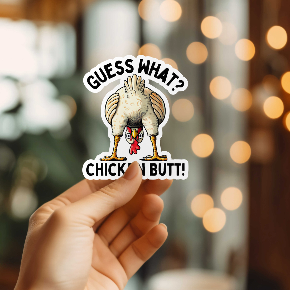Hand holding a sticker with a chicken graphic and text against a blurred background with lights