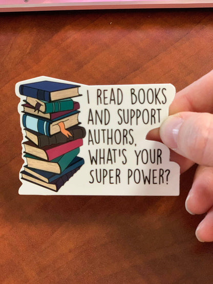 Hand holding a sticker with books and text on a wooden surface