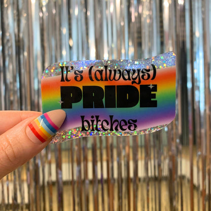 Rainbow-colored card with text held by a hand against a metallic curtain background