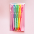 A set of six colorful gel pens in a clear plastic sleeve with a pink and white gingham patterned backing. The pens are labeled &