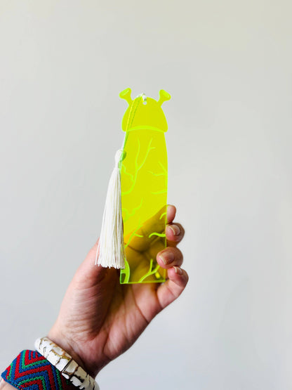 Hand holding a yellow ogre shaped bookmark on a plain background
